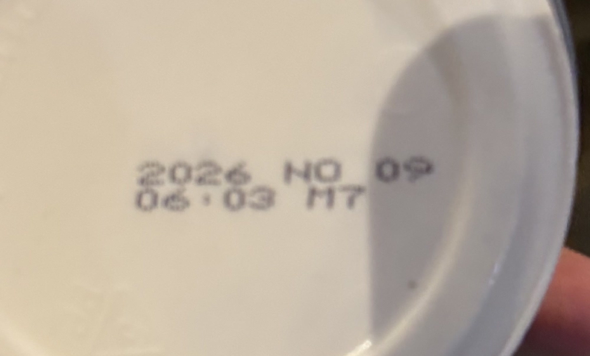 A faint expiry date printed around the curved lid of a cream cheese container.