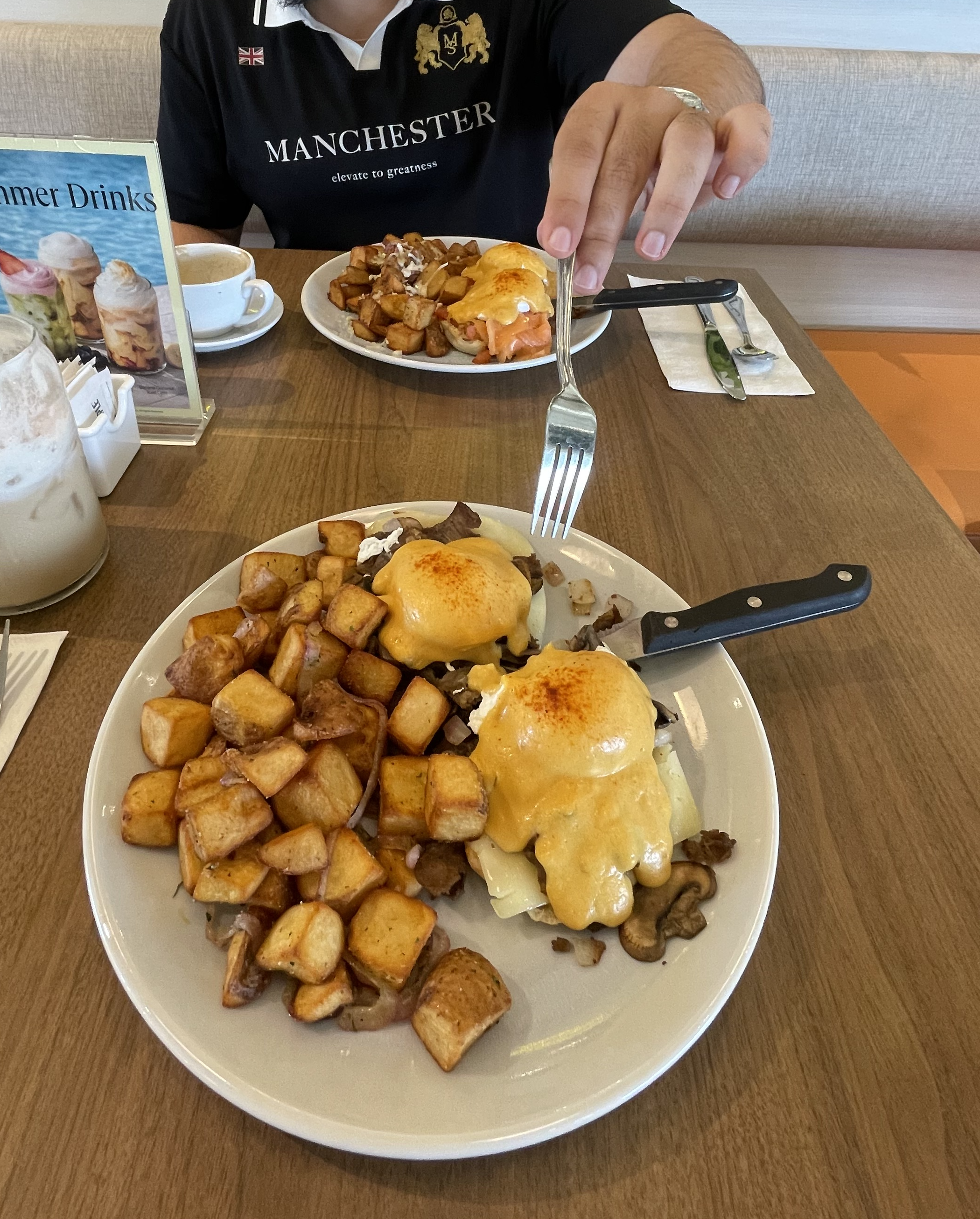Two plates of eggs Benedict and breakfast potatoes at brunch.