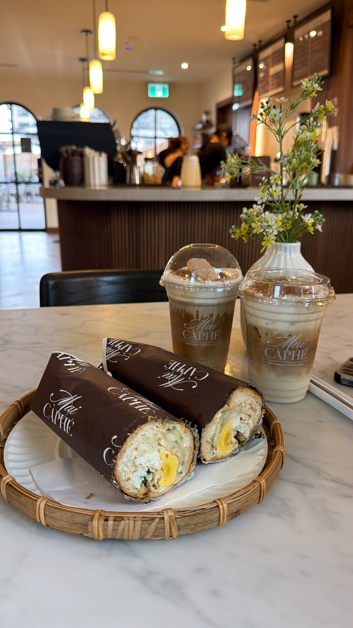 Two café sandwiches and iced drinks on a table.