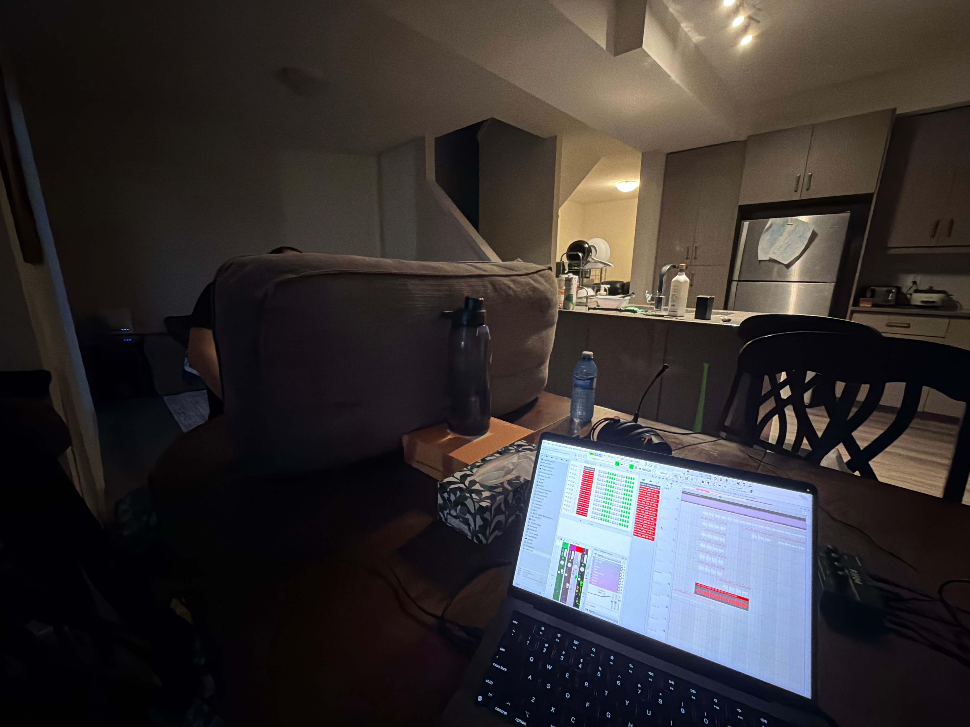 A makeshift music studio at a friend's house, with FL Studio open on a laptop at the table.