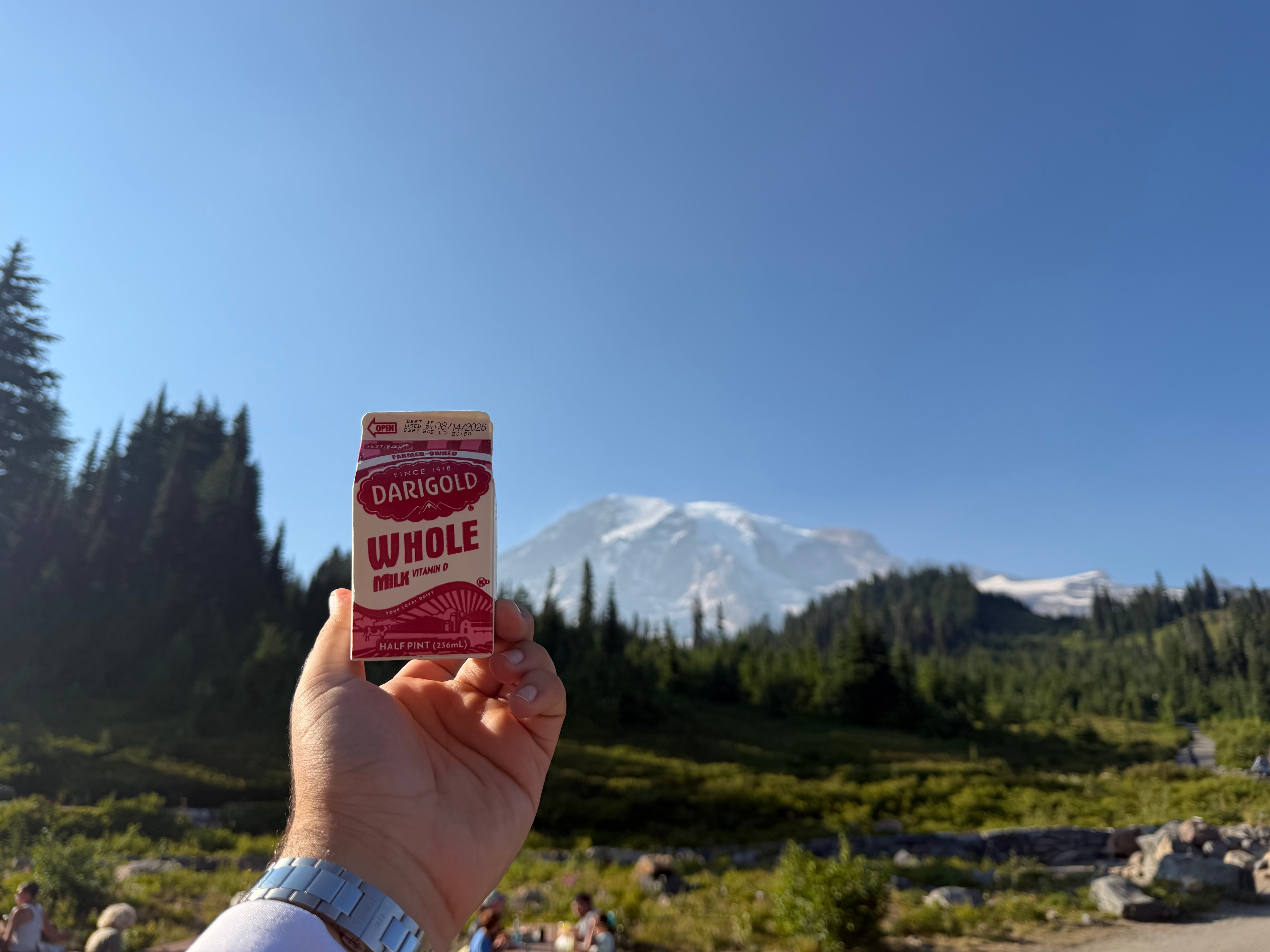 Shaaf holding a small carton of whole milk with Mount Rainier in the background.