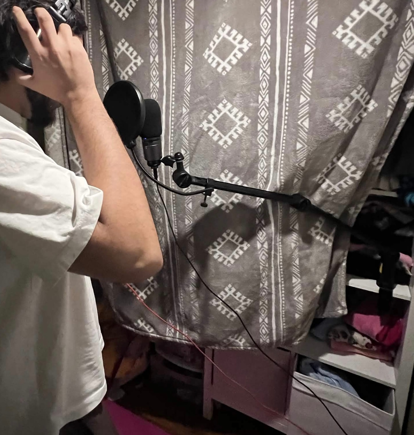 Shaaf recording vocals with a microphone and a makeshift acoustic setup.