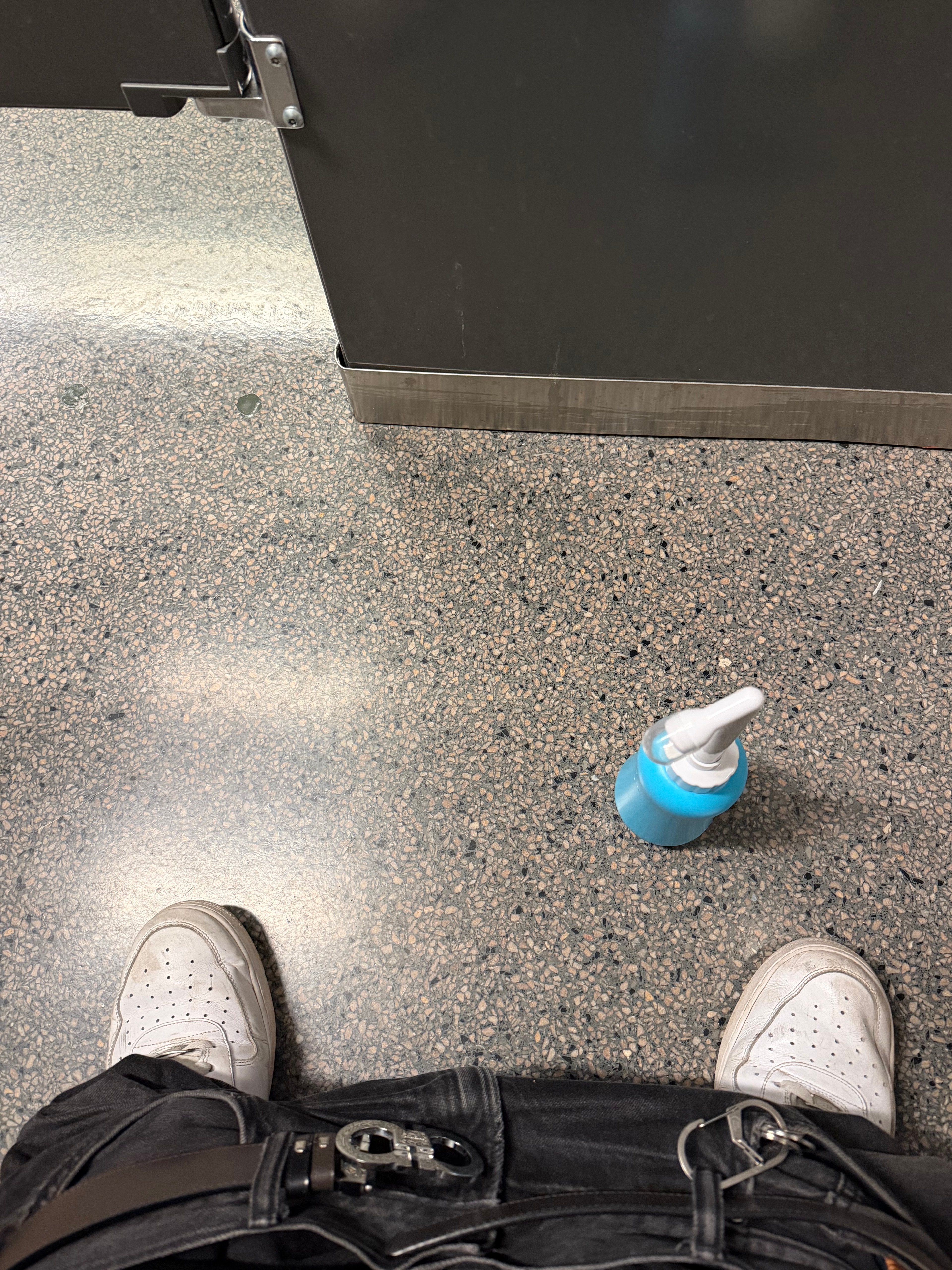 Shaaf's shoes and a blue soap bottle on a public restroom floor.