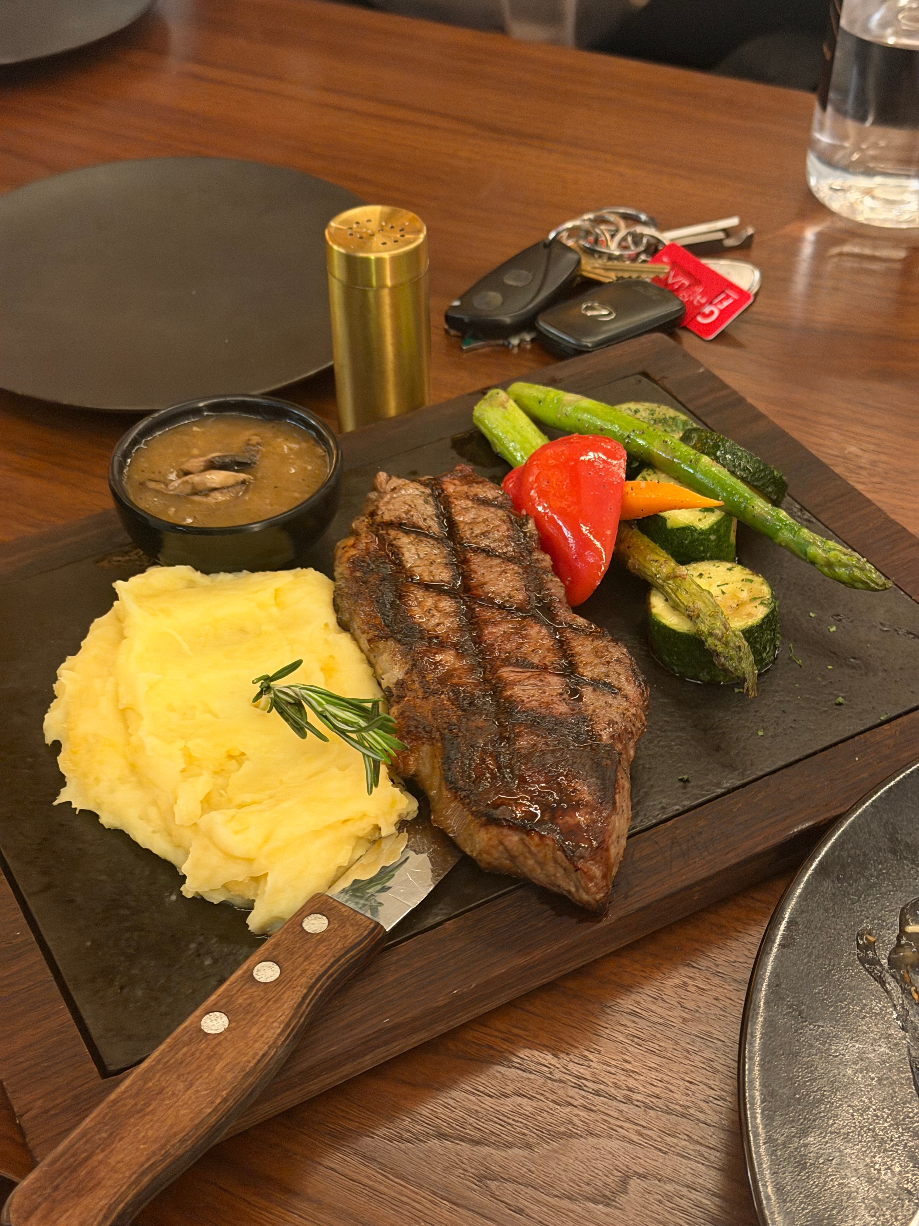 A steak dinner with mashed potatoes and grilled vegetables.